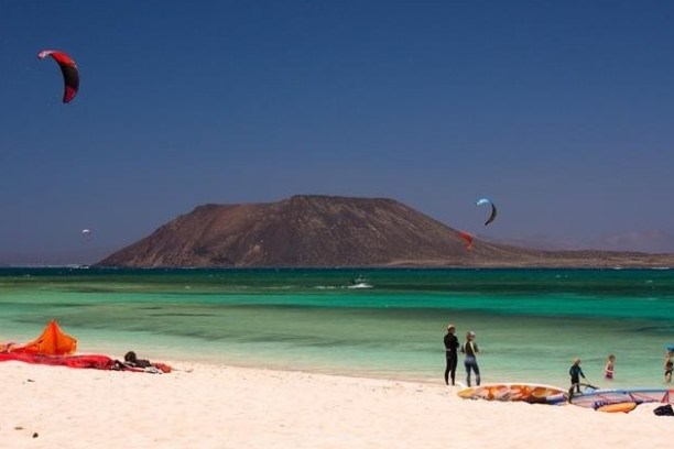 a group of people kite surfing on the beach