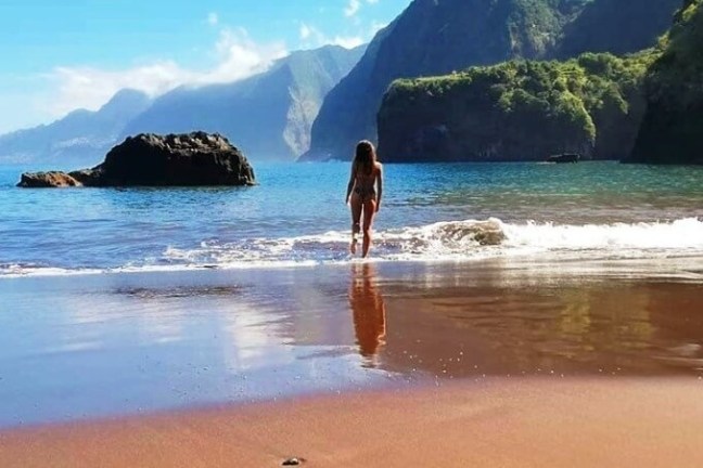 a woman standing on a rocky beach