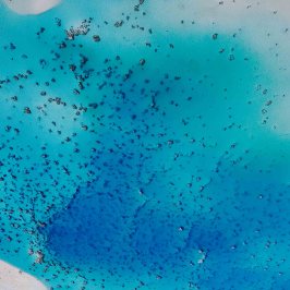 Aerial view of a bright blue ocean with scattered dark patches.
