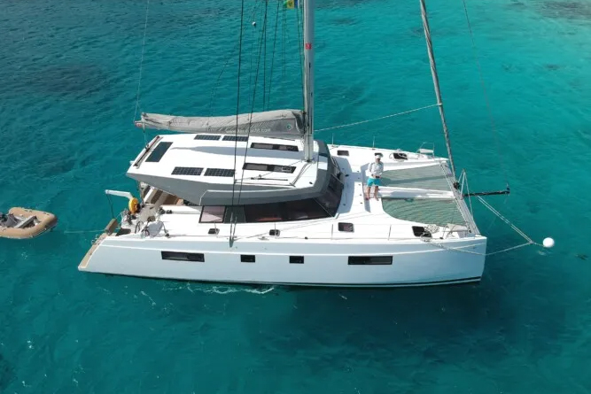 Catamaran sailing on clear blue water, with visible deck and sail