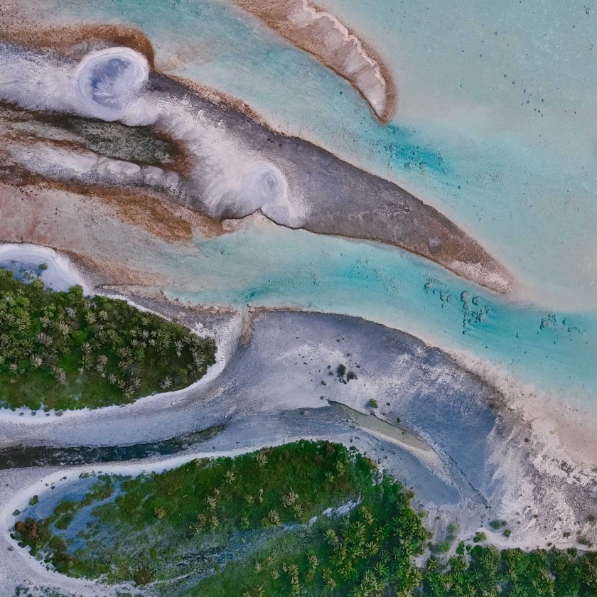 Aerial view of coastal landscape with turquoise water and green vegetation islands.