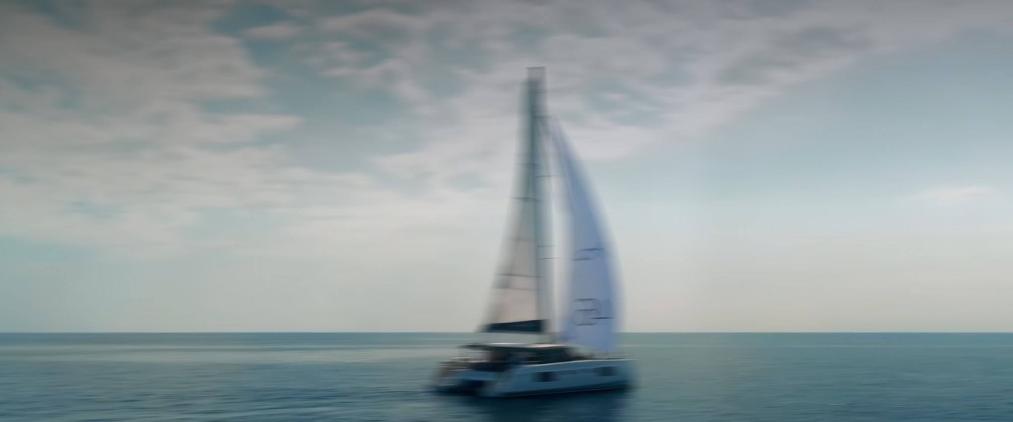 Sailboat on calm sea under a partly cloudy sky.
