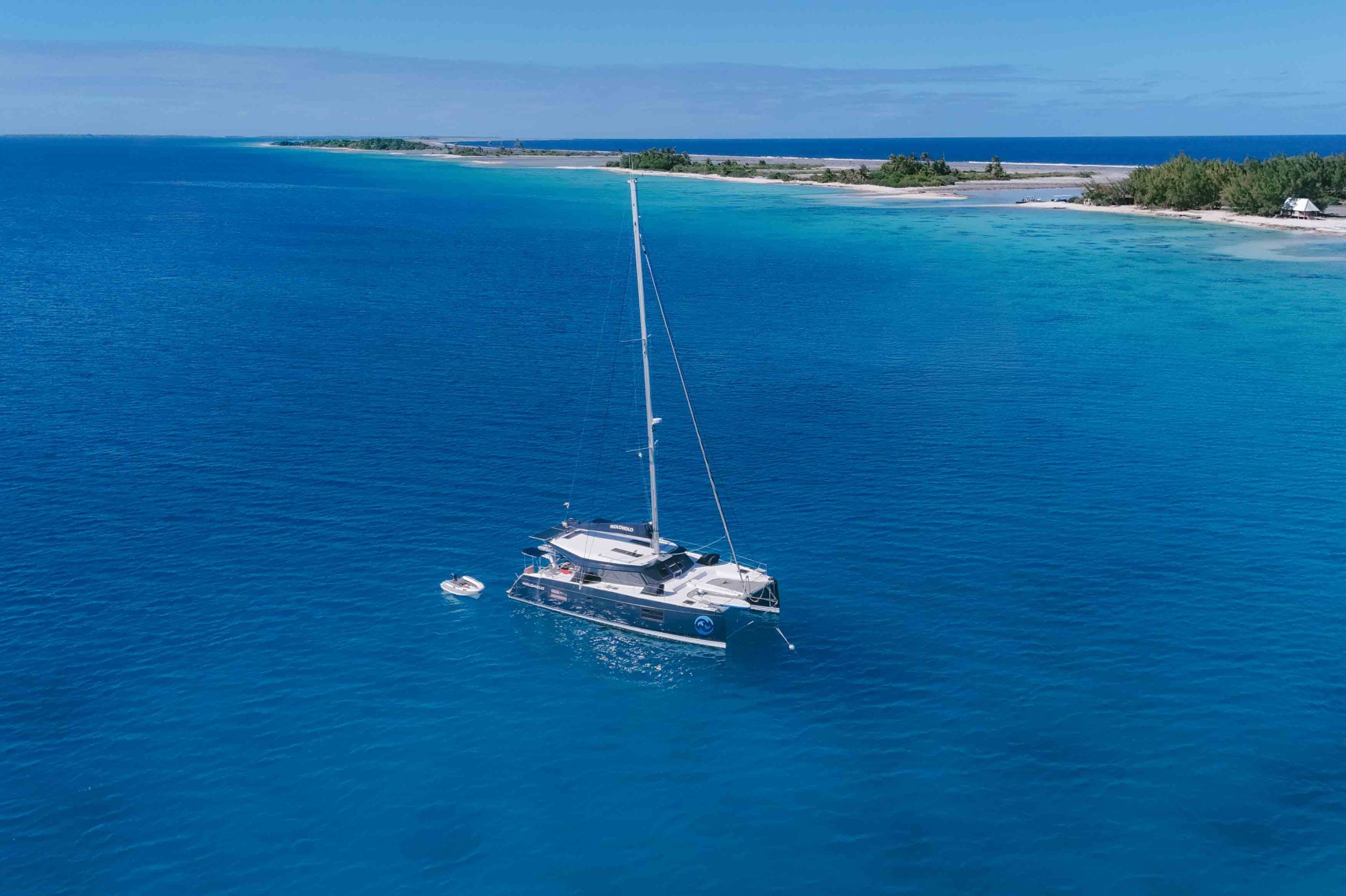 Sailboat anchored in turquoise waters near a distant island.