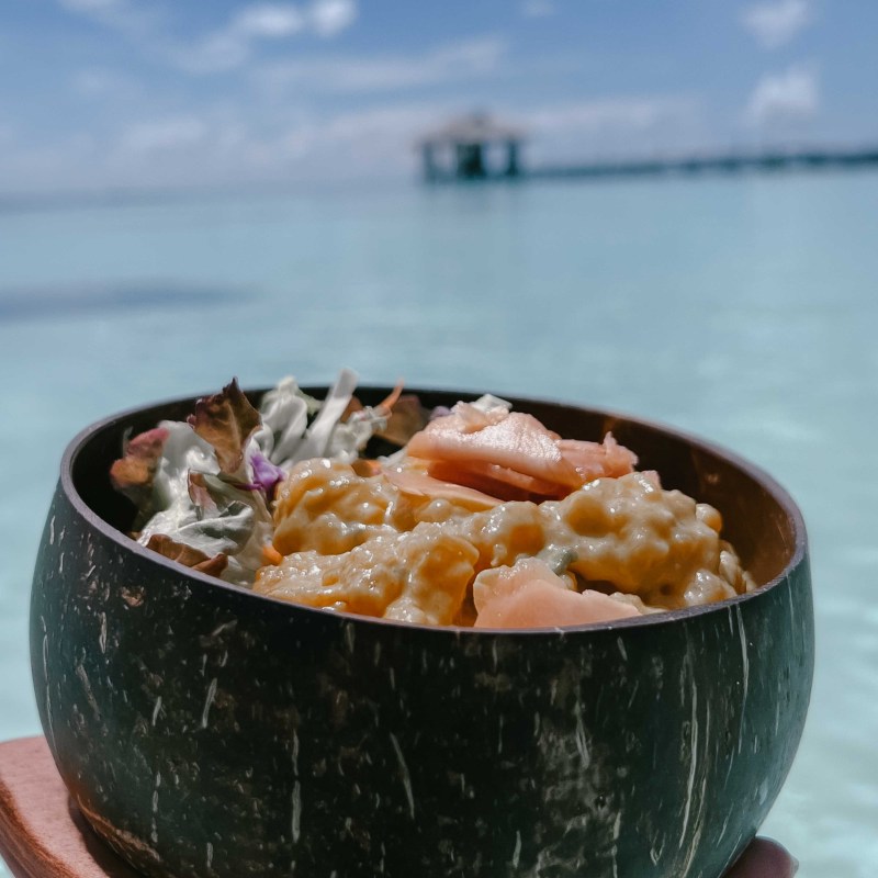 A coconut bowl with seafood salad by the sea.