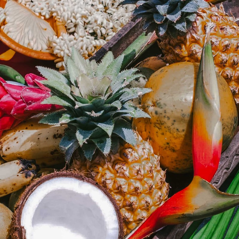 Tropical fruits including pineapples, bananas, coconut, and decorative flowers.
