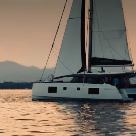 Sailboat on calm water at sunset with distant mountains.