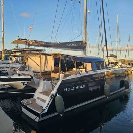 Marina with a large, sleek catamaran named Holo Holo docked beside smaller boats.