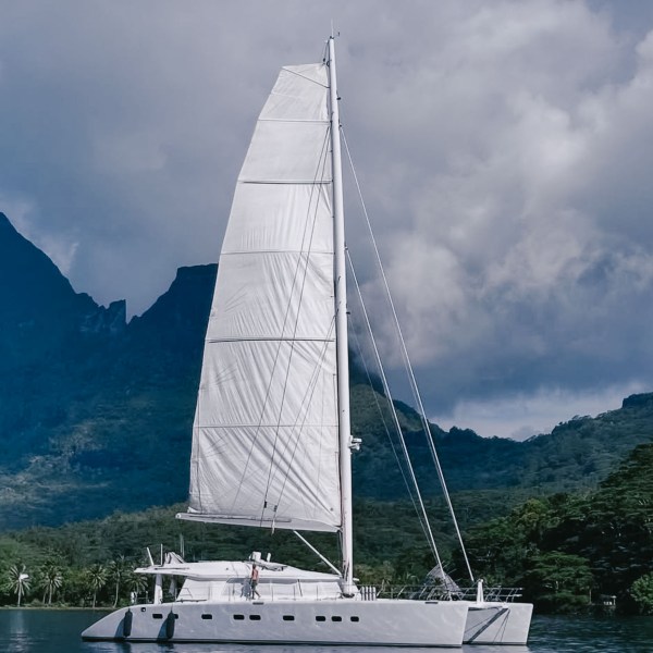 Sailboat on calm water with mountains in the background.
