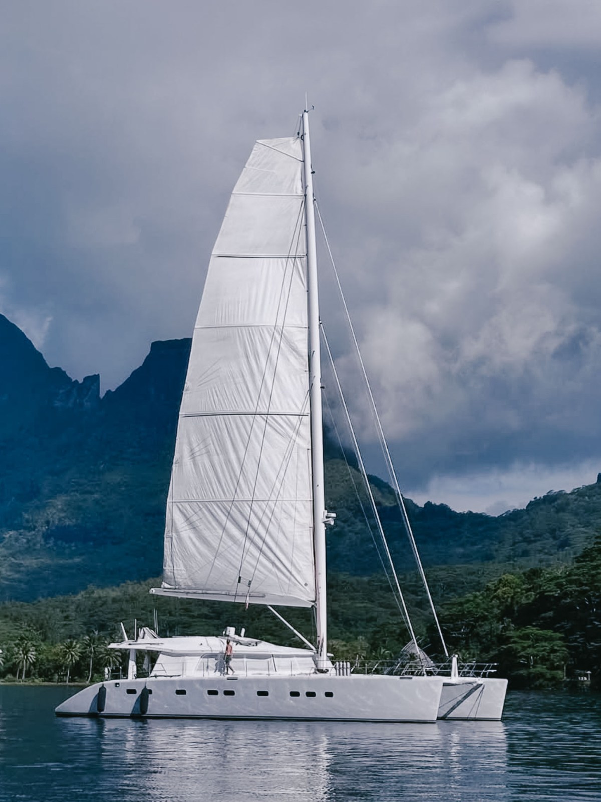 Sailboat on calm water with mountains in the background.