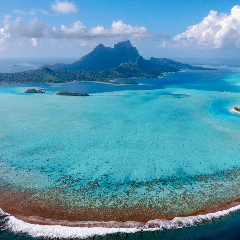 Aerial view of turquoise waters and mountain on a tropical island.