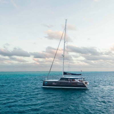 Sailing yacht on calm ocean under partly cloudy sky during daytime.