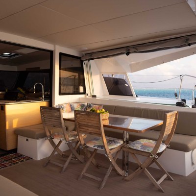 Sunny yacht interior with dining set, cushions, and ocean view.