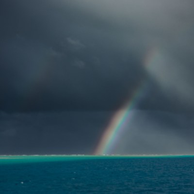 Rainbow over dark ocean under stormy sky.