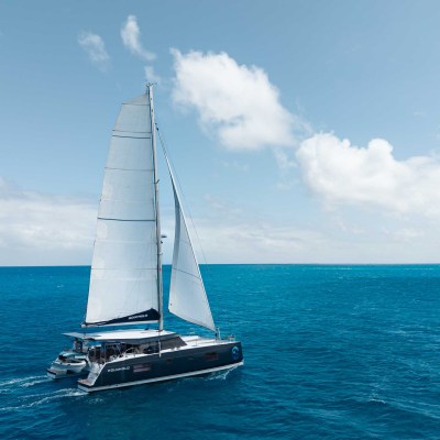 Sailboat on the open sea with blue sky and clouds.