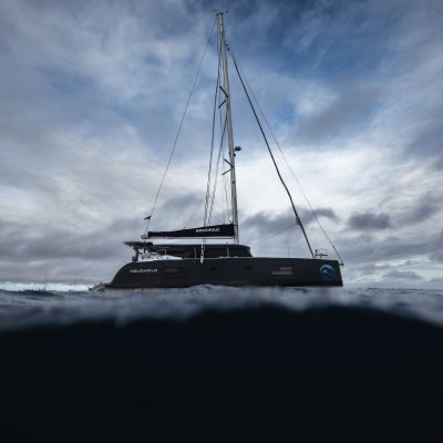 Sailboat on the ocean with cloudy sky and low horizon.
