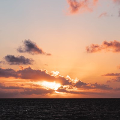 Sunset over the ocean with orange clouds and dark sea.