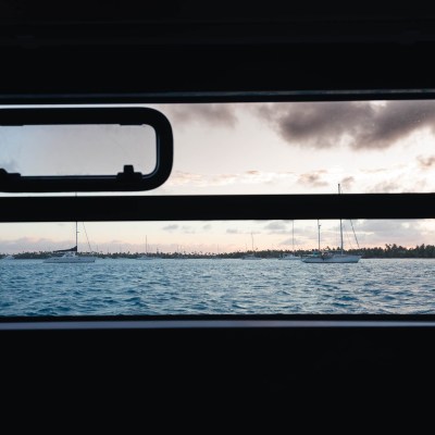 View through window of sailboats on ocean at sunset.