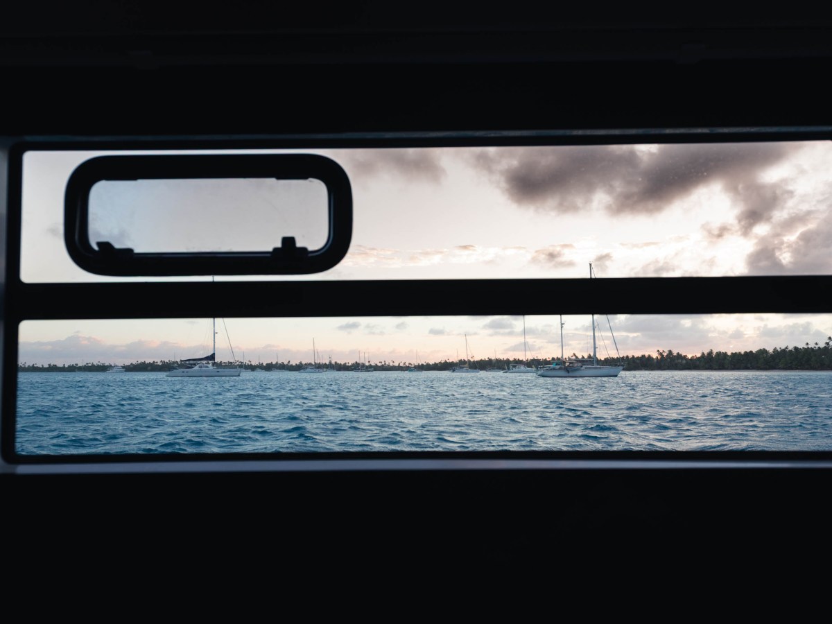 View of sailboats on ocean through a window at sunset.